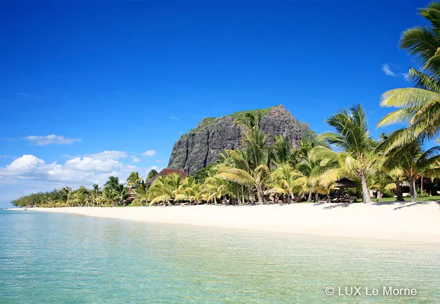 Mauritius: Kleiner Felsberg umringt von Palmen auf einem Sandstrand
