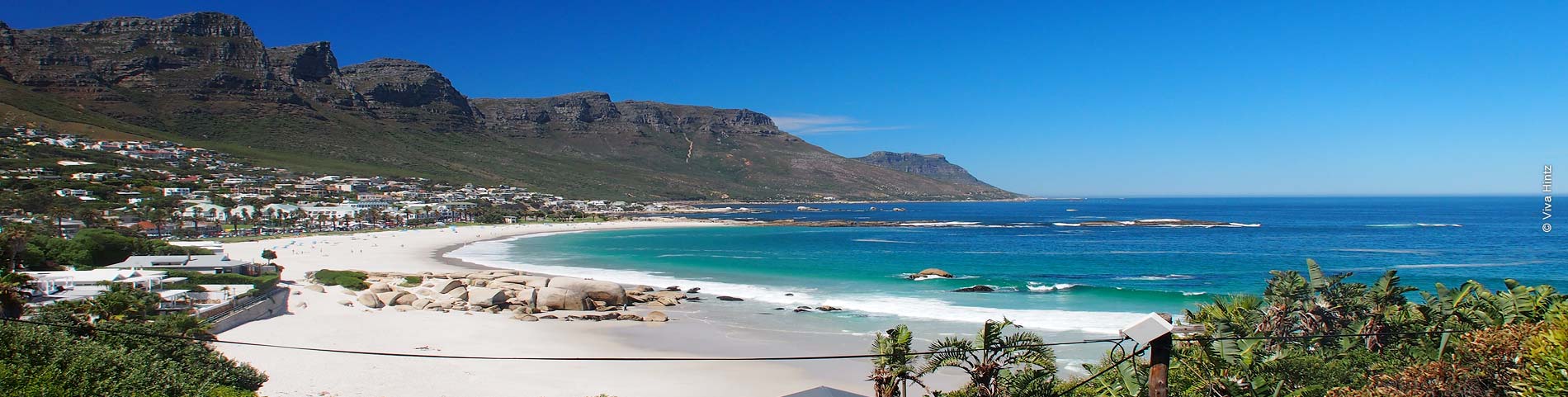Großer Sandstrand mit blauem Meer umringt von Bergen