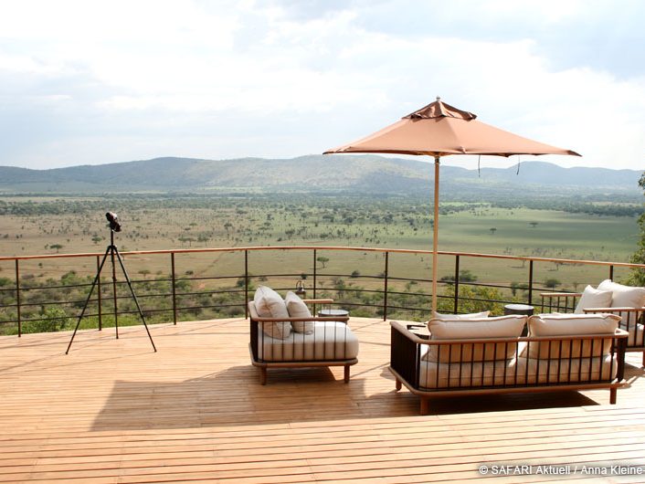 Holzterrasse mit Fernglas und Sitzgelegenheit mit Sonnenschirm. Wunderschöne weite Aussicht auf die Natur und Berglandschaft.