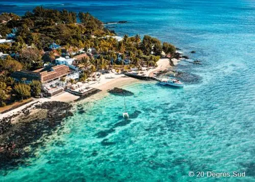 Kleine Insel mit Bäumen und Hotelanlage im azurblauen Meer